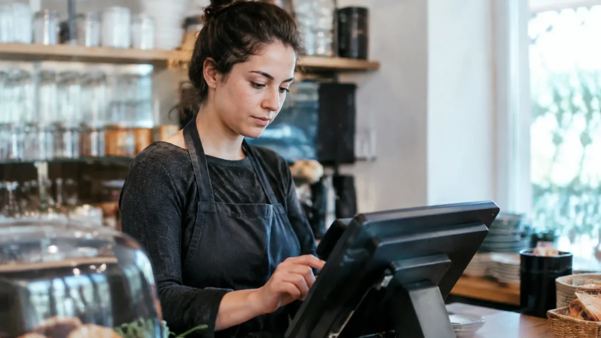 Commercant debout derriere comptoir tapant sur ecran tactile