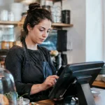 Commercant debout derriere comptoir tapant sur ecran tactile