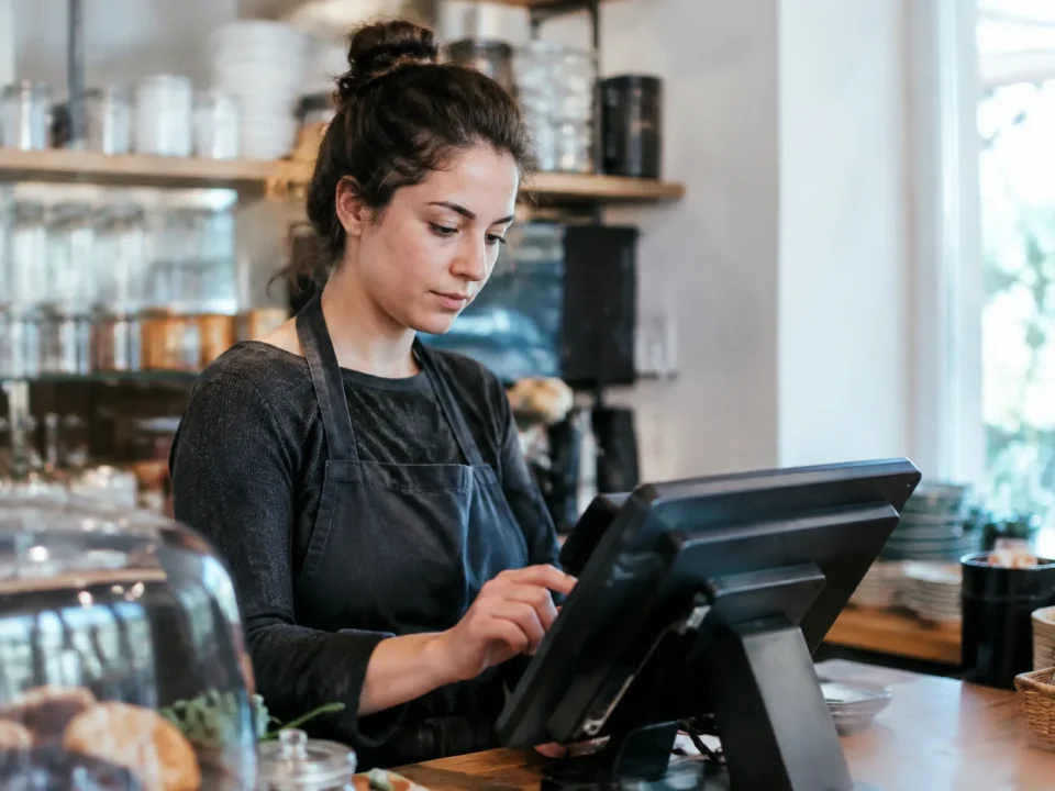 Commercant debout derriere comptoir tapant sur ecran tactile