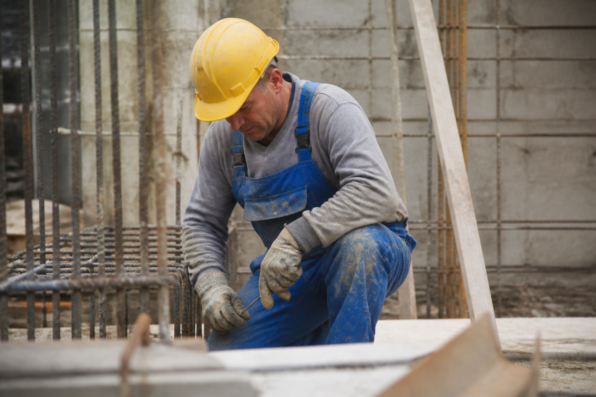 Ouvrier en salopette bleue avec casque jaune sur chantier