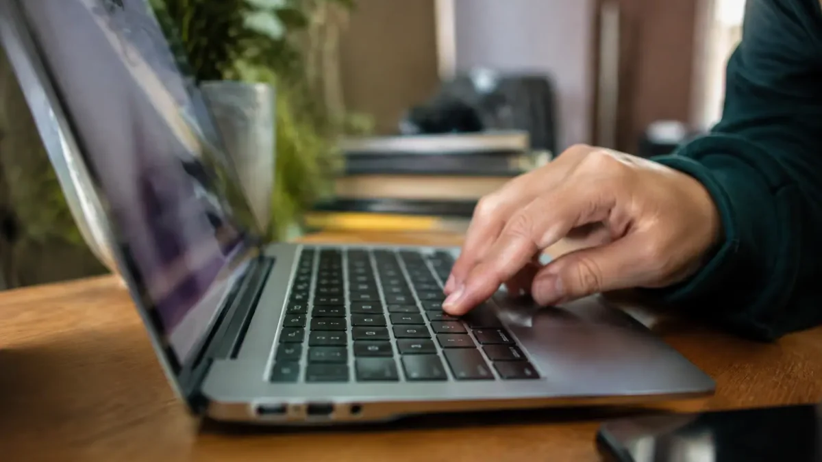 Portable ouvert sur un bureau, doigt pressant une touche