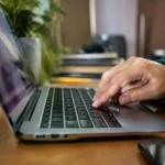 Portable ouvert sur un bureau, doigt pressant une touche