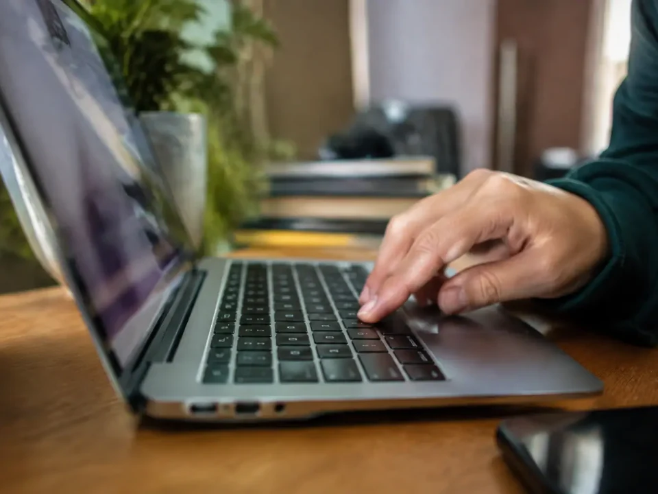 Portable ouvert sur un bureau, doigt pressant une touche