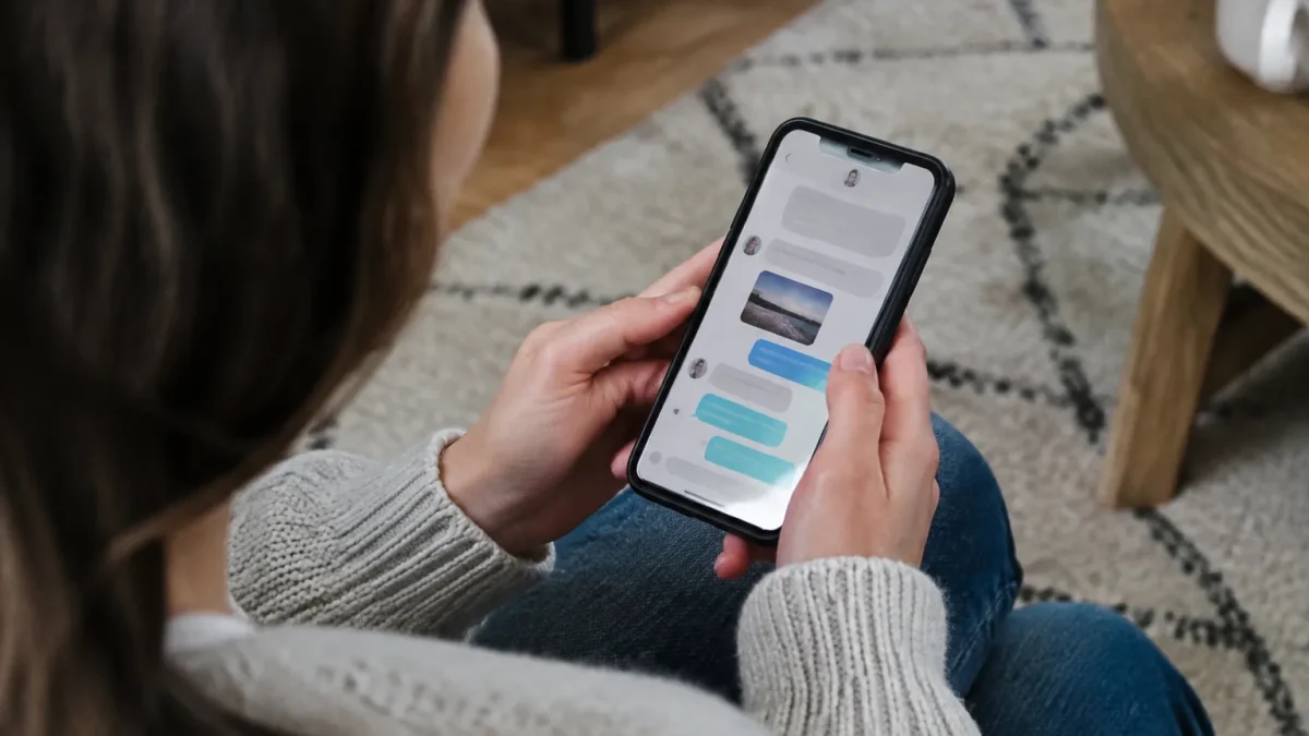 Main tenant un smartphone affichant une conversation de messages