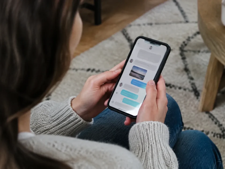 Main tenant un smartphone affichant une conversation de messages