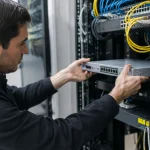 Technicien branche un boitier gris sur un rack reseau