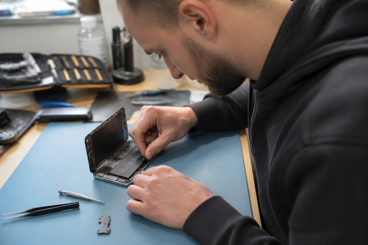 Technicien remplace la batterie iPhone sur un etabli